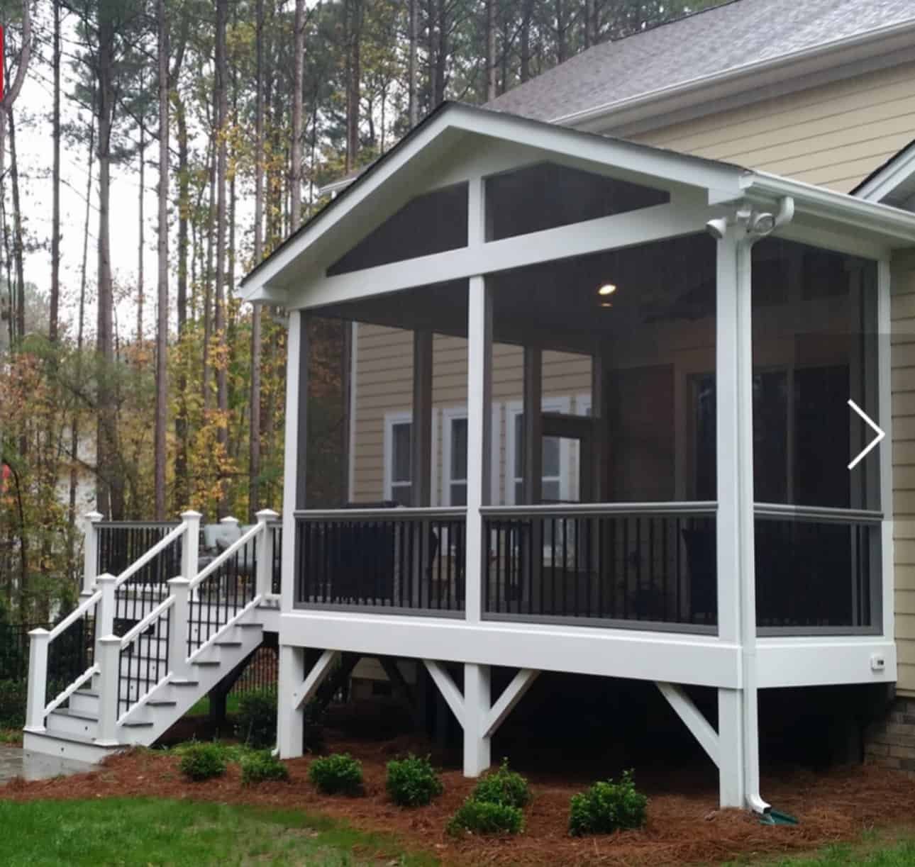 Enclosed porch with stairs and railing, perfect for outdoor relaxation and protection from weather.