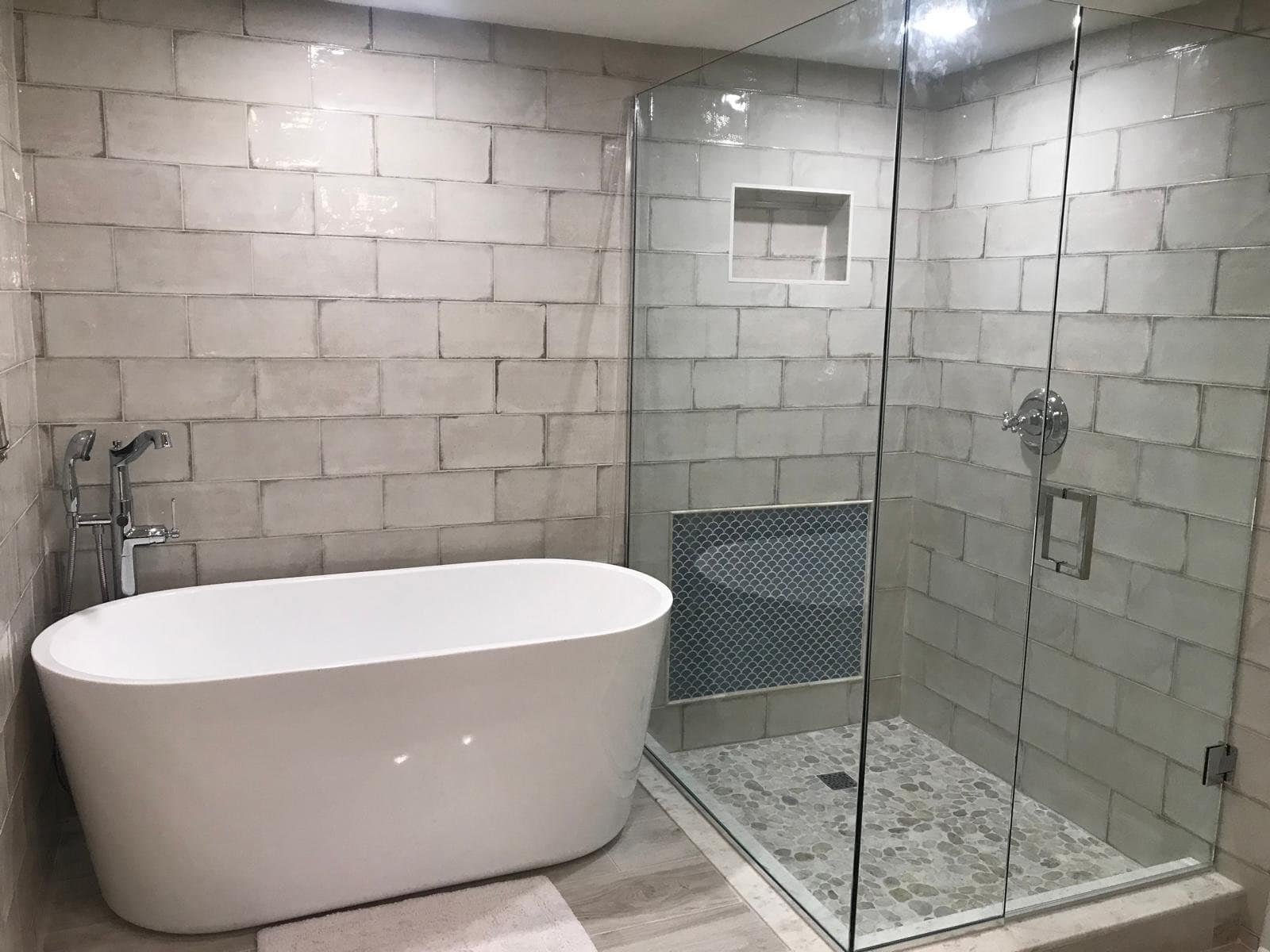 Freestanding bathtub and glass shower enclosure in a contemporary bathroom setting.