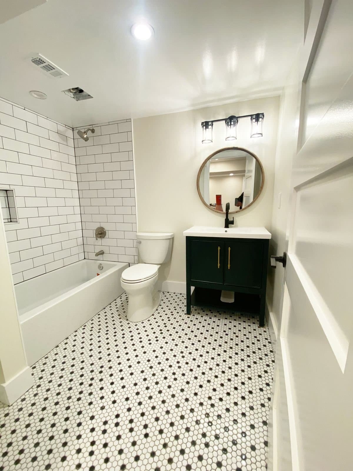 Stylish bathroom with white subway tiles, black and white patterned floor, and contemporary vanity.